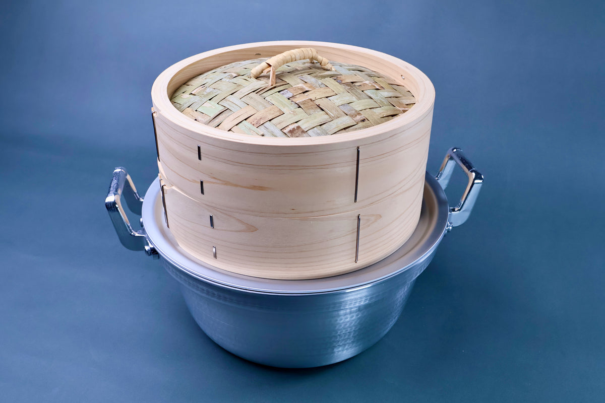 Bamboo steamer kit 21cm assembled showing woven bamboo lid with rattan handle, cedar body in hammered aluminum pot on blue background