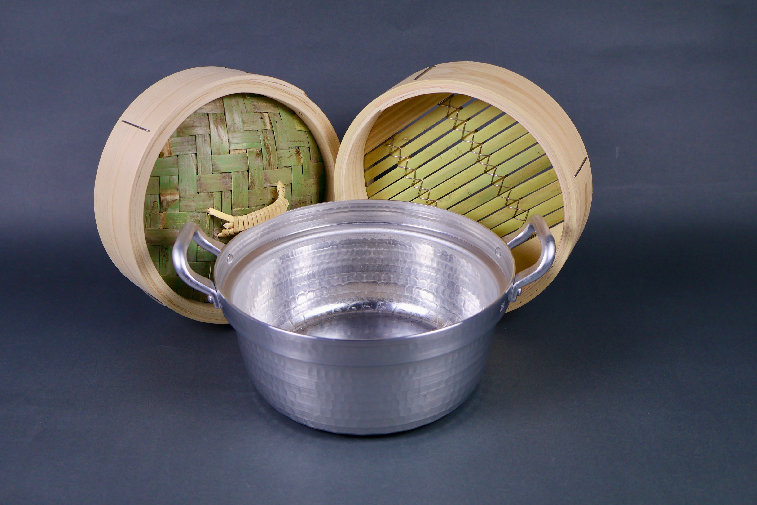 bamboo steamer kit four pieces hammered metallic pot two handles bamboo thick wood steamer lid and base metallic circular steam ring center hole grey background