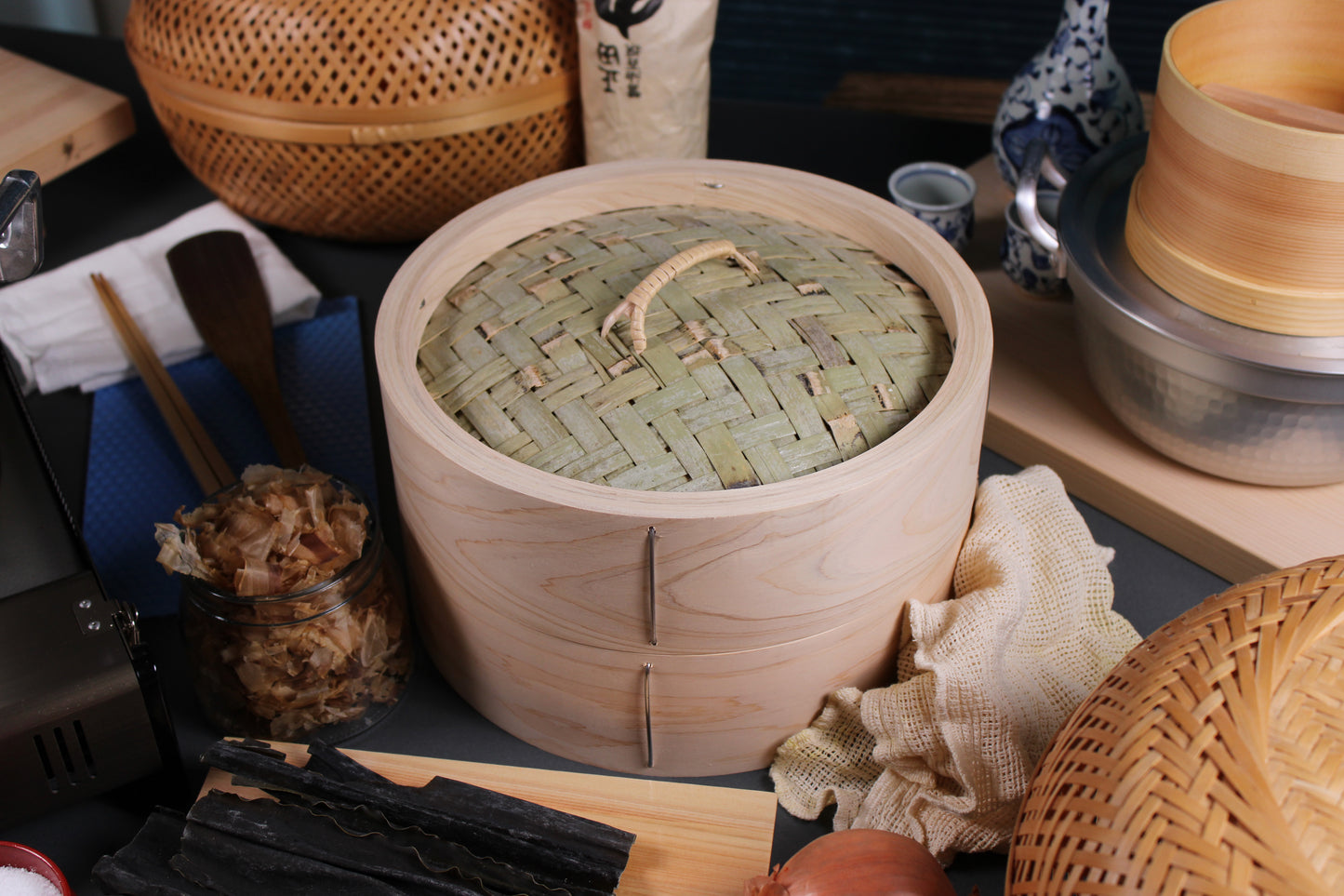 top down view dining table shot of bamboo hinoki chinese style seiro steamer with base and side of kiso hinoki surrounded by ingredients of kombu kelp shaved bonito flakes seiro steamer pot with hinoki tofu maker by yamacoh yoshino hinoki cutting board by hanabusa by tsuji wood technical