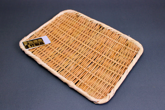 woven bamboo strainer rectangular tan brownish in color with product tag showing contrasting gold black kanji characters in grey blue backdrop