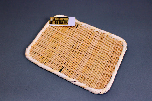 woven bamboo strainer rectangular tan brownish in color with product tag showing contrasting gold black kanji characters in grey blue backdrop