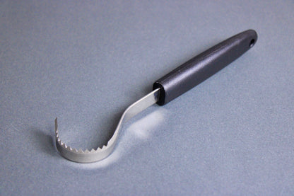 long thin black plastic handled stainless steel curved serrated tool butter curler on grey background