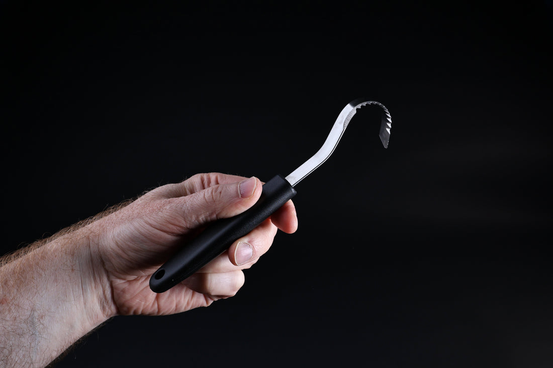 Butter curler and vegetable tool — curved blade profile and serrated edge detail held in hand