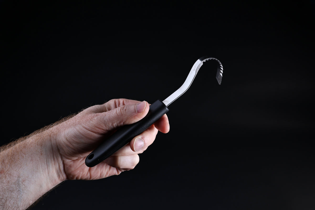 Butter curler and vegetable tool — curved blade profile and serrated edge detail held in hand