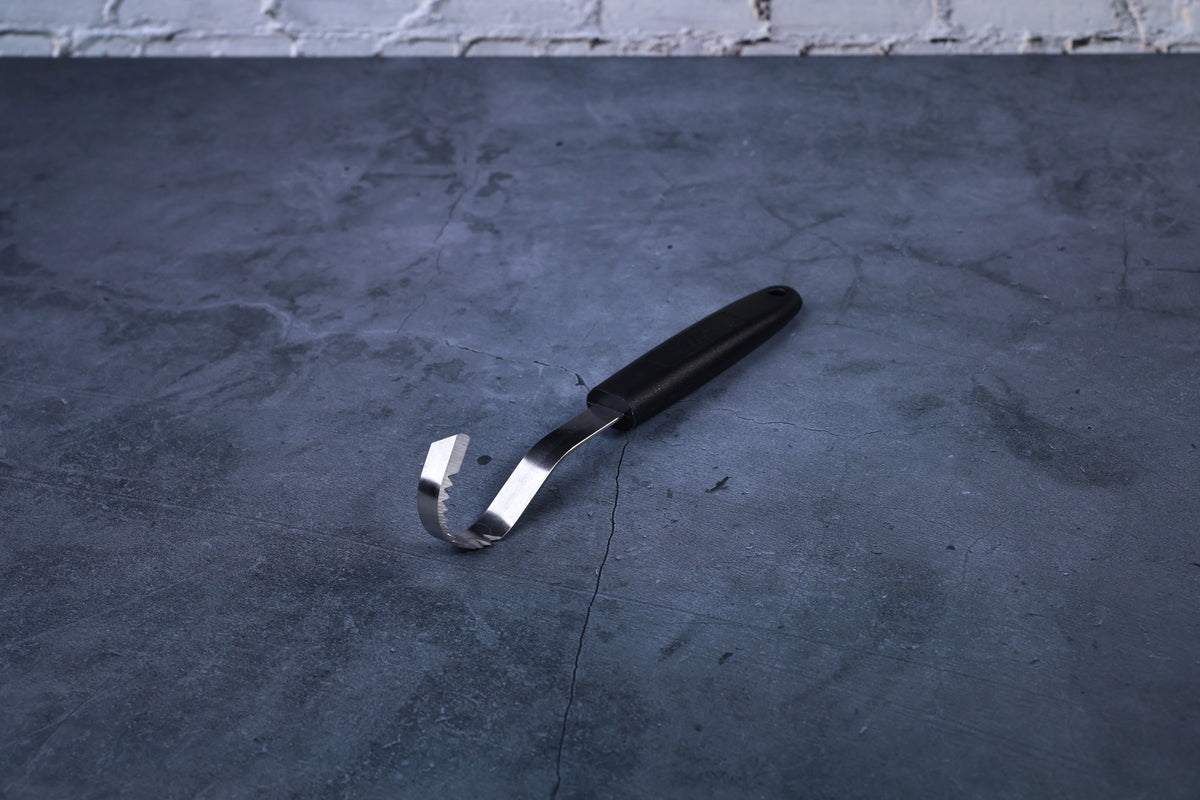 Butter curler and vegetable tool — full view showing curved serrated blade and black handle on concrete