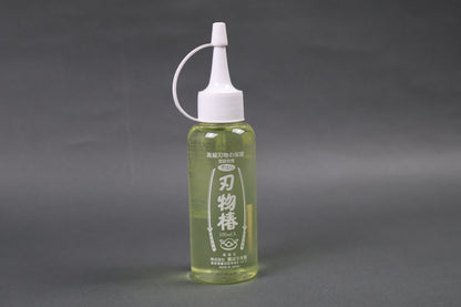 camelia oil used in kitchens to prevent knife rust cast iron rust tool maintenance upright shot showing light yellow oil in container with kanji characters animated swords white cap dripper 