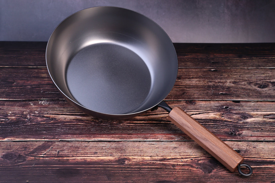 Carbon Steel Nitride deep fry pan 26cm overhead angled view showing full interior and walnut handle on wood