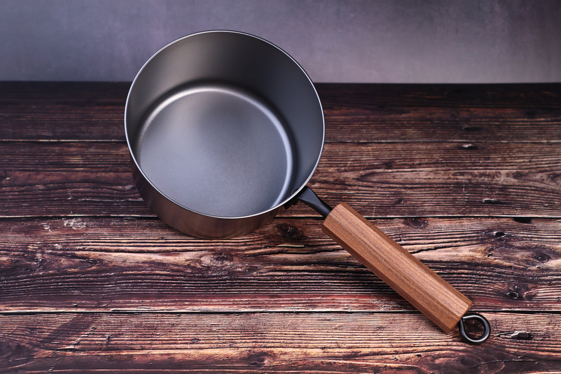 Carbon Steel Nitride saucepan 16cm overhead angled view showing full interior and walnut handle on wood