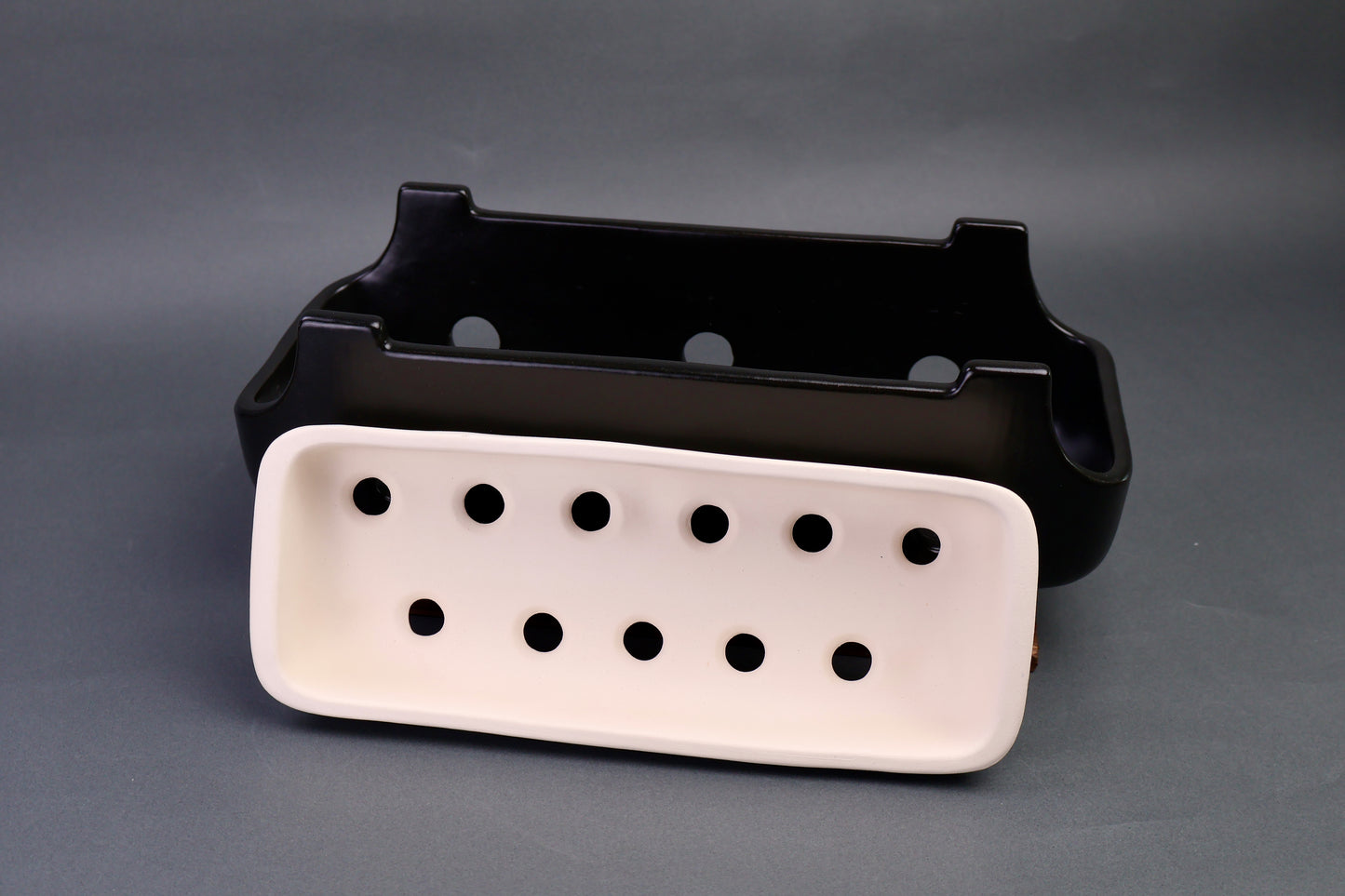 black glazed ceramic yakitori grill with interior white charcoal tray in front in grey background 