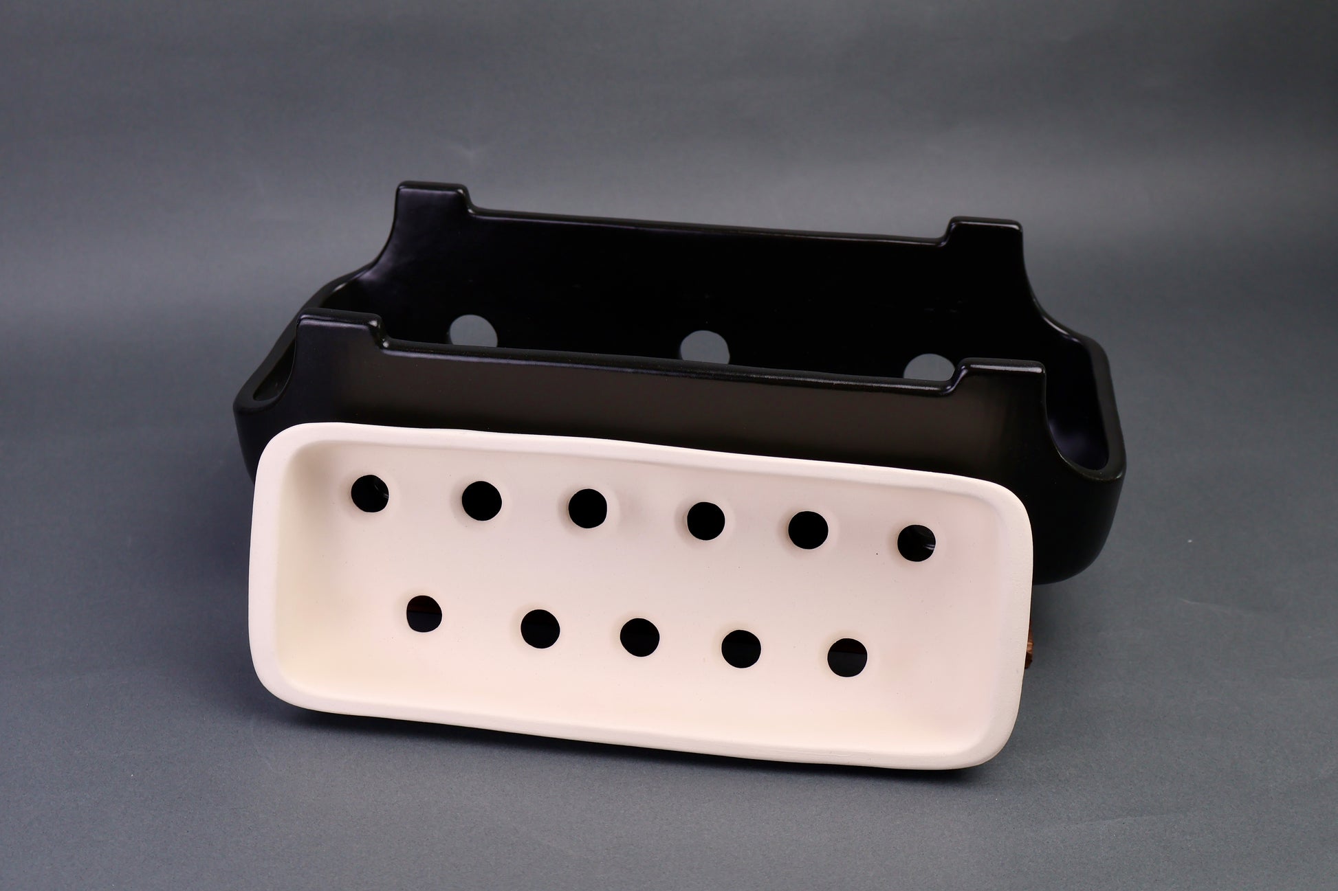 black glazed ceramic yakitori grill with interior white charcoal tray in front in grey background 