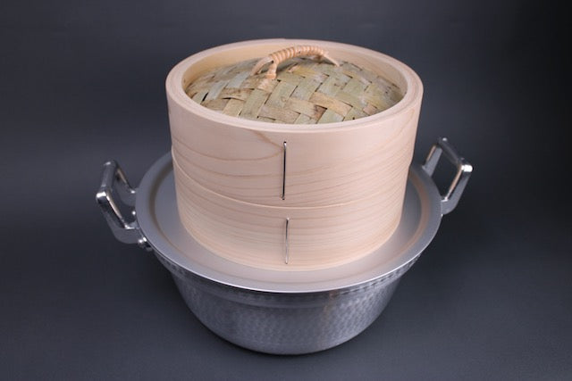 chinese style round and tall bamboo steamer made of hinoki with base and lid sitting atop aluminum 24cm steam ring and dantsuki seiro steamer made of aluminum two handles grey background