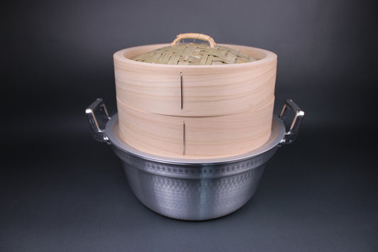 handmade steamer kit featuring steamer lid with thick durable walls made of kiso hinoki and base featuring bamboo slats woven in place with stainless steel wire exact sure fit fitting atop dantsuki steamer pot with two large handles in front of a dark grey background