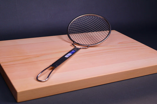 stainless steel coarse skimmer on a wooden cutting board with a dark background