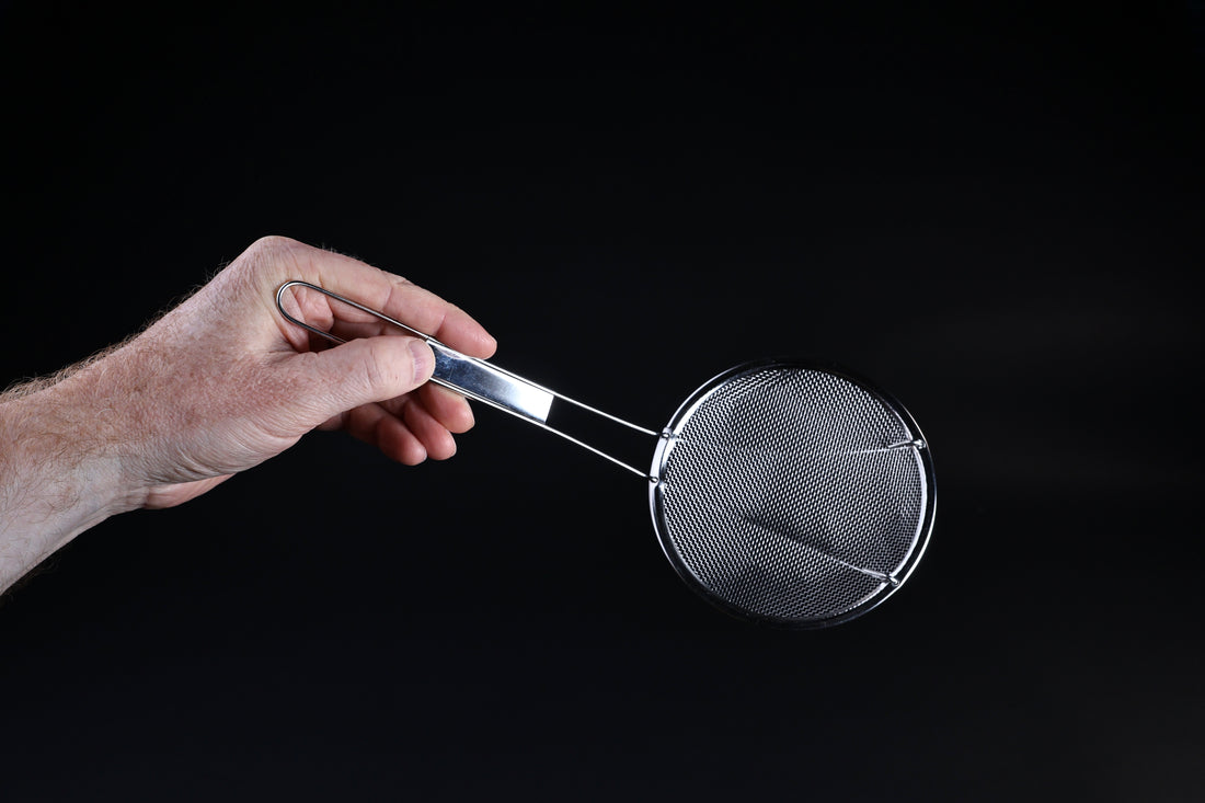 Coarse mesh skimmer — face-on view of wire mesh basket and stainless rim held in hand