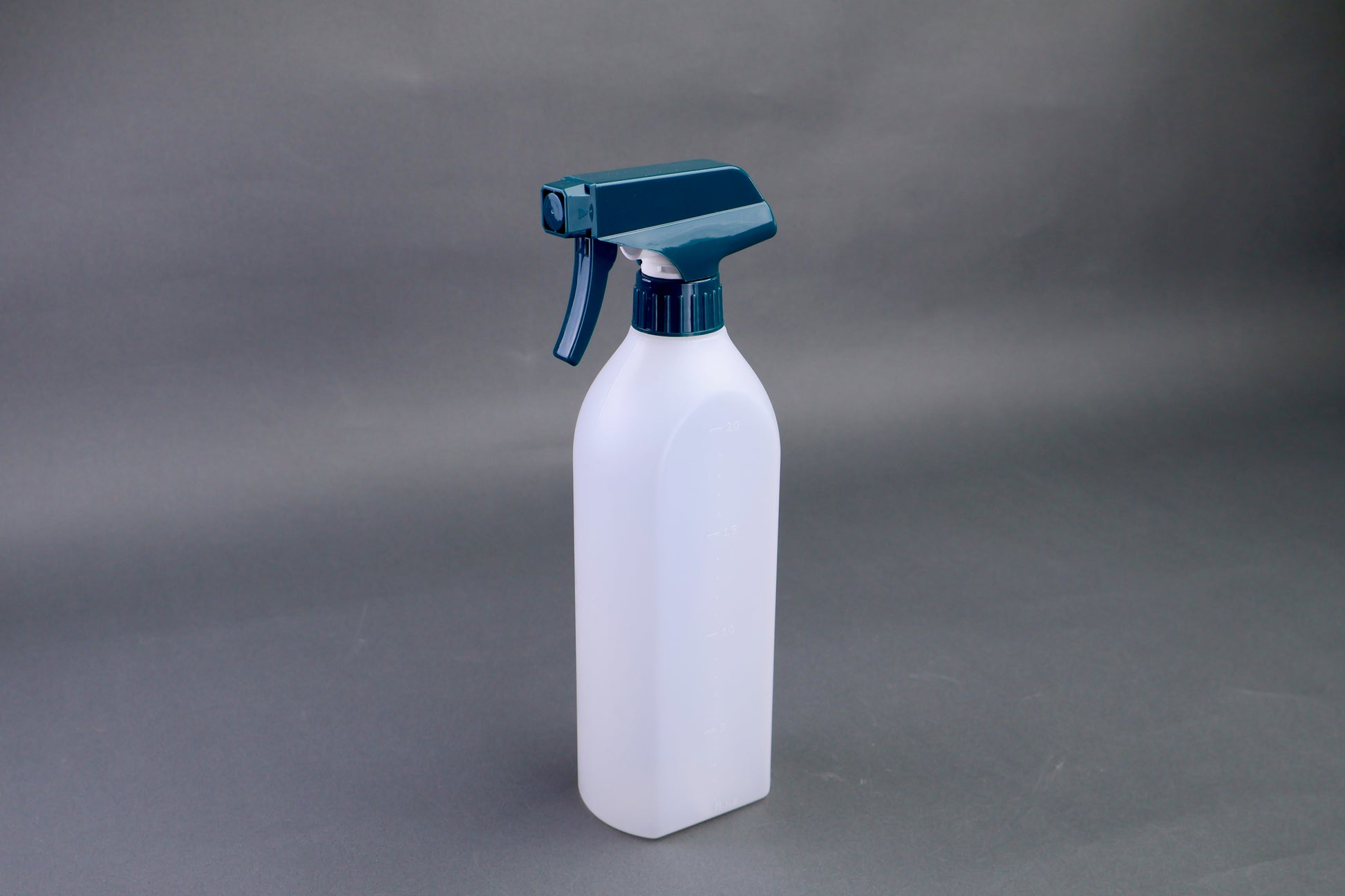 White spray bottle with a blue nozzle on a gray background