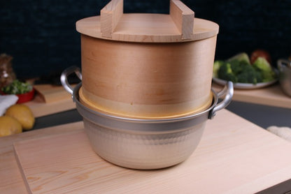 detail shot of dantsuki steaming pot with round handmade hinoki wood steaming basket sitting on top with wood lid and handle with kitchen background showing japanese cookware