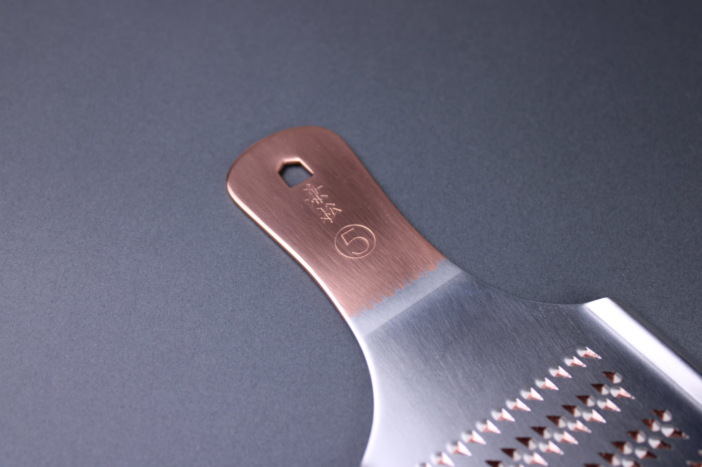 detail of copper handle kanji of kanematsu and number five size with grey background 
