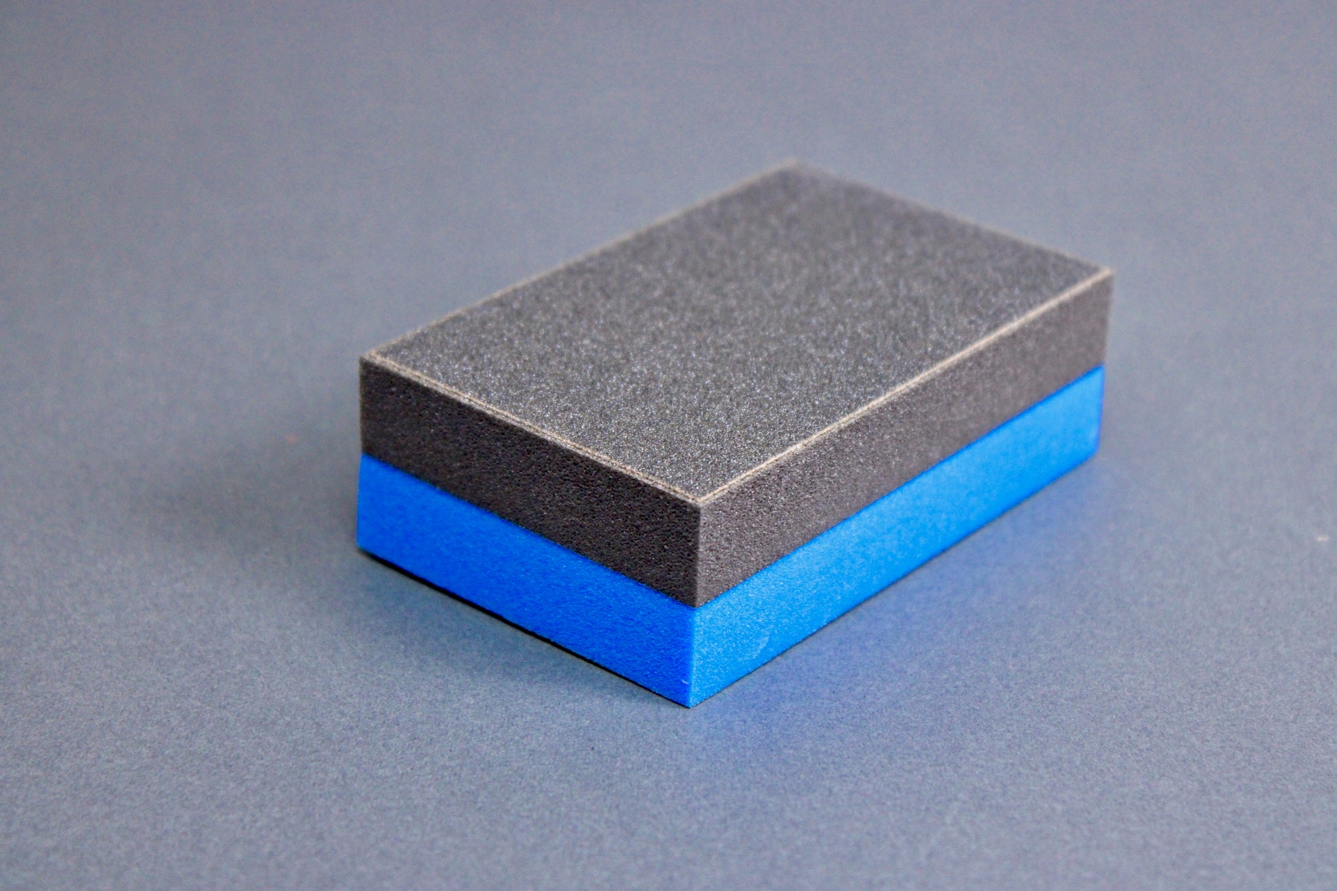 rectangular half black half blue cutting board scrapper sitting atop grey surface