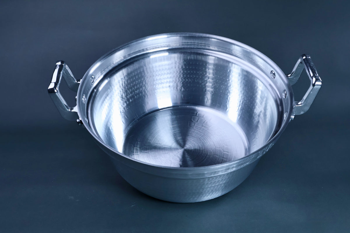 Dantsuki seiro pot 27cm angled view showing hammered aluminum interior walls and brushed base with chrome handles on blue-grey background