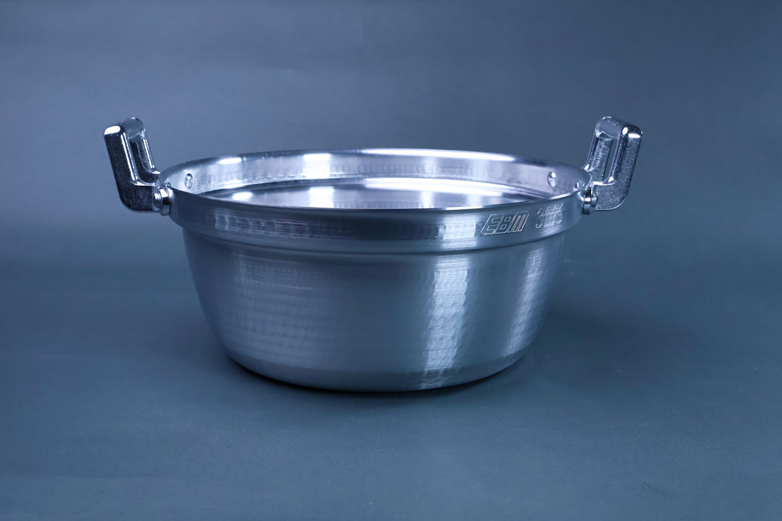Dantsuki seiro pot 30cm exterior three-quarter view showing hammered aluminum finish and chrome handles on blue-grey background