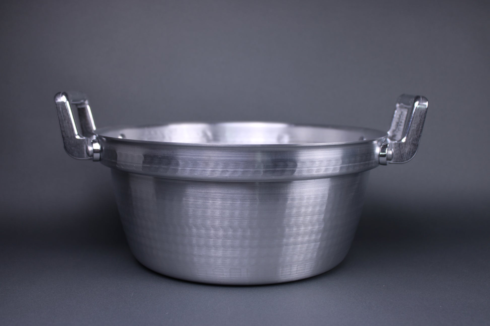  level view steaming pot with two handles stepped ledge for steam basket hammered surface with grey background
