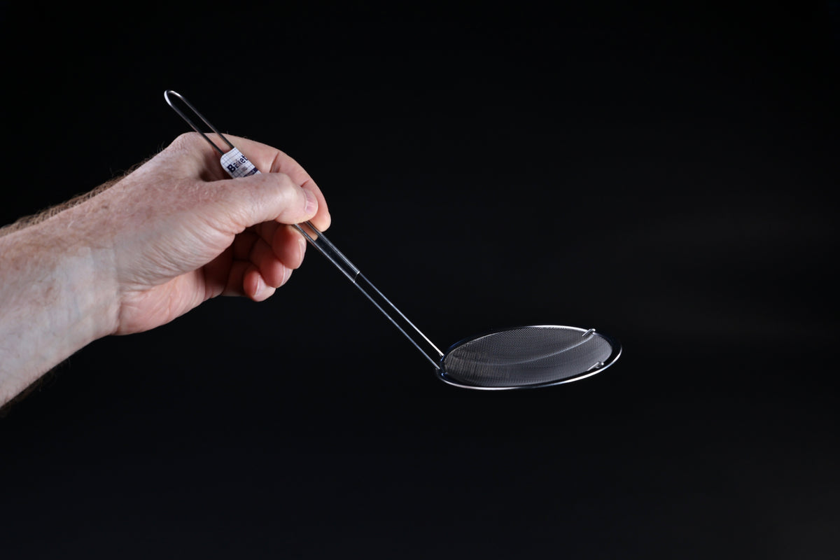 Fine mesh skimmer — side profile showing shallow basket depth and wire handle angle in hand