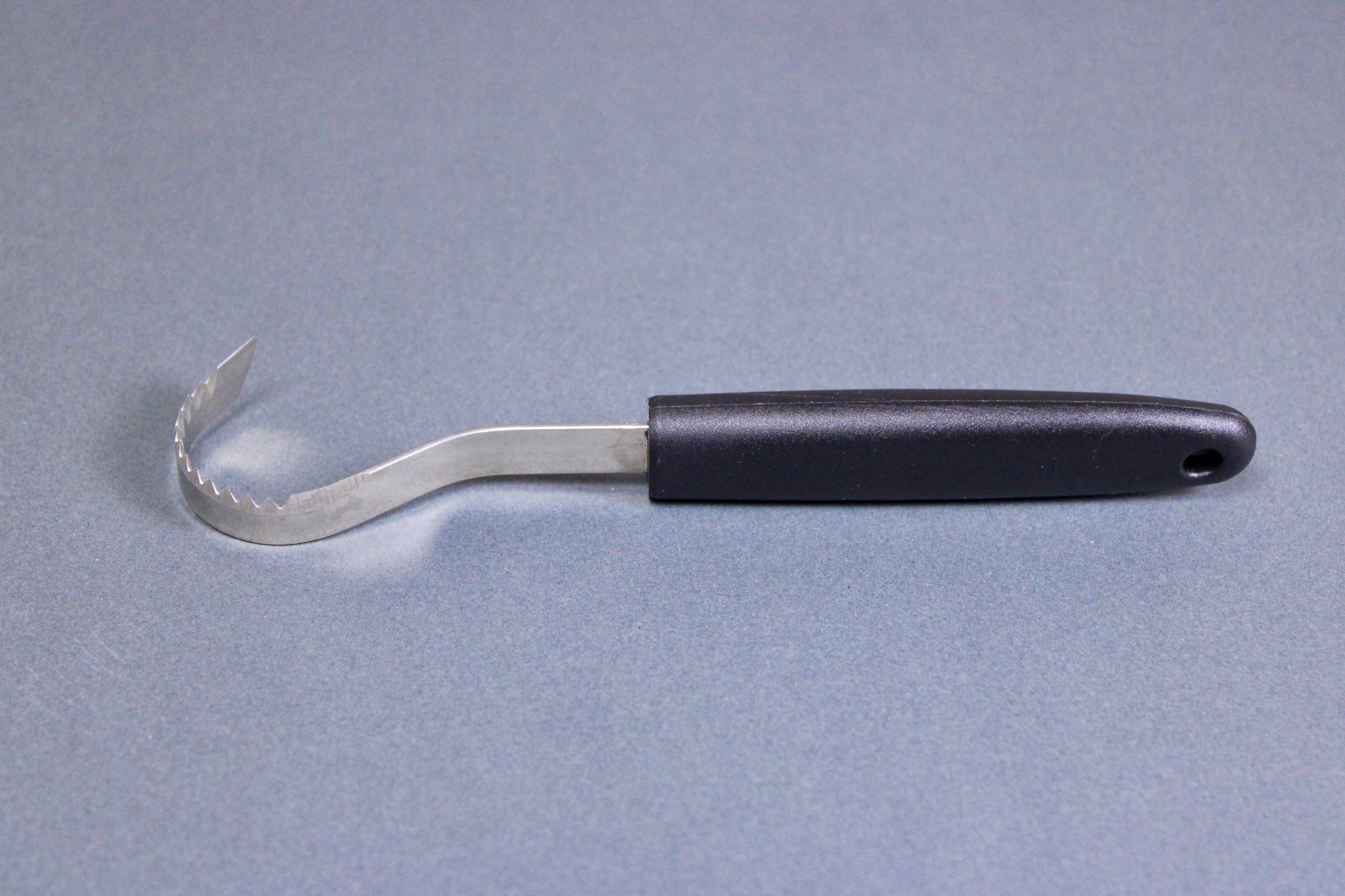 long thin black plastic handled stainless steel curved serrated tool butter curler on grey background