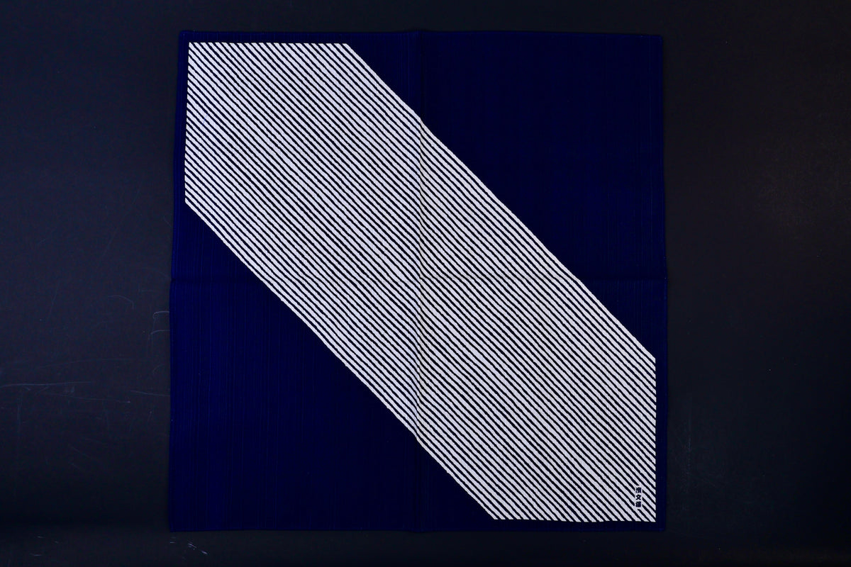Hamamonyo classified stripes black tenugui fully unfolded on dark background, showing diagonal stripe design against solid navy