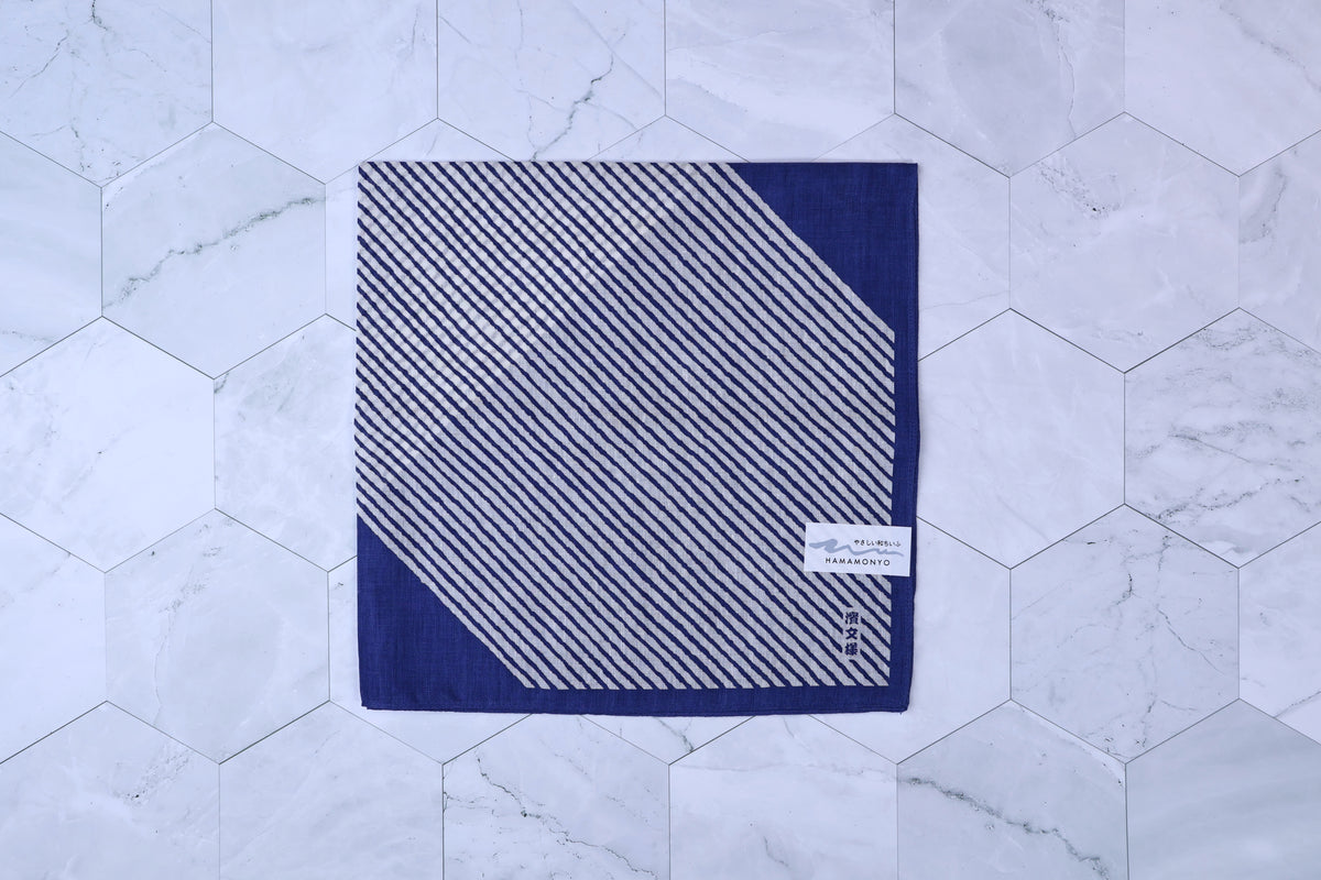 Hamamonyo classified stripes blue tenugui folded on white hex tile, diagonal stripe pattern and Hamamonyo label visible