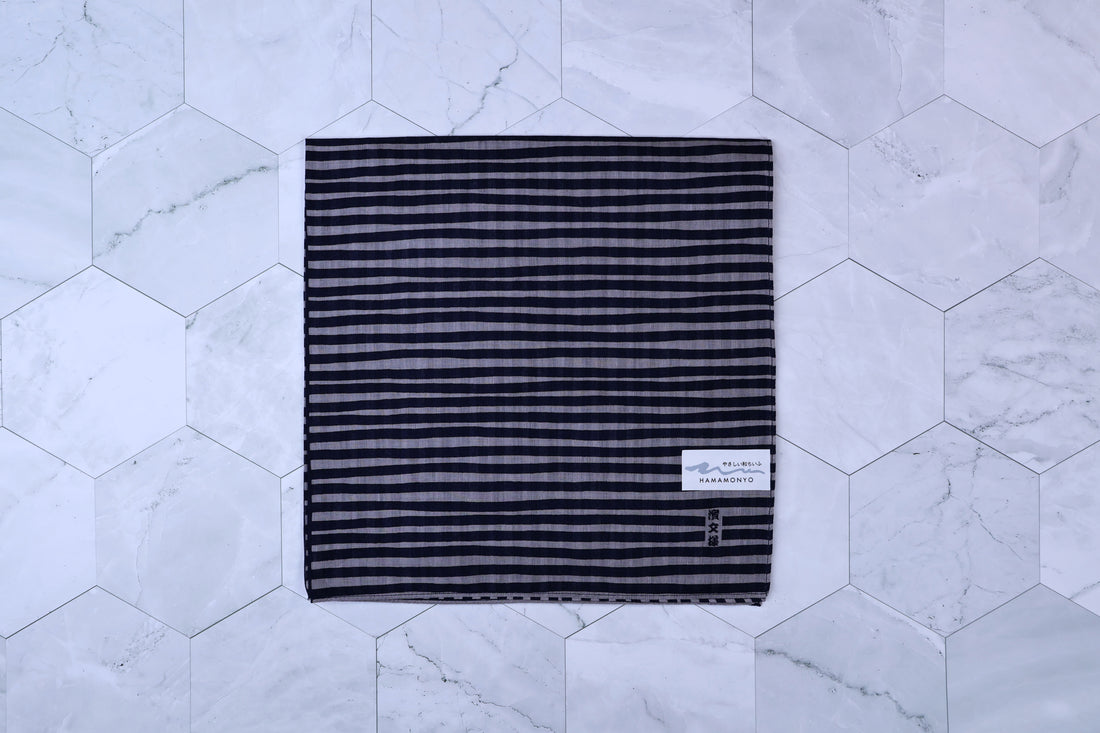 Hamamonyo tateyoko striped tenugui folded flat on white hex tile, Hamamonyo label visible in corner