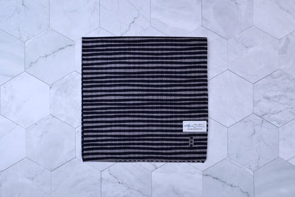 Hamamonyo tateyoko striped tenugui folded flat on white hex tile, Hamamonyo label visible in corner