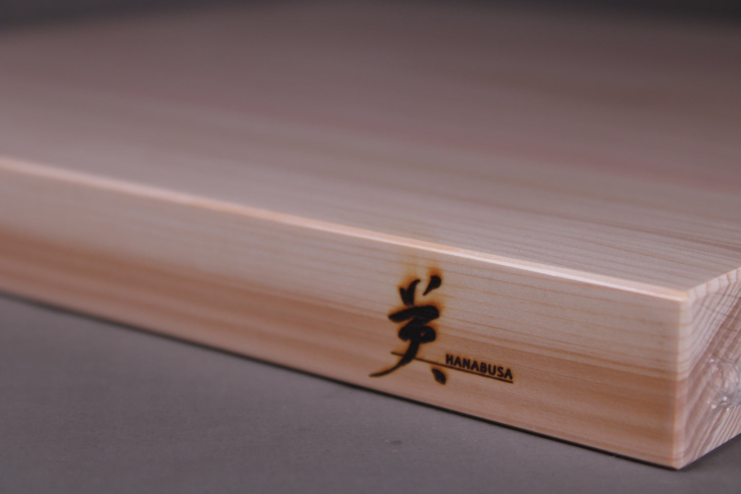 detailed shot of hinoki wood cutting board showing grain pattern and hanabusa logo and beveled edges silk finish surface 