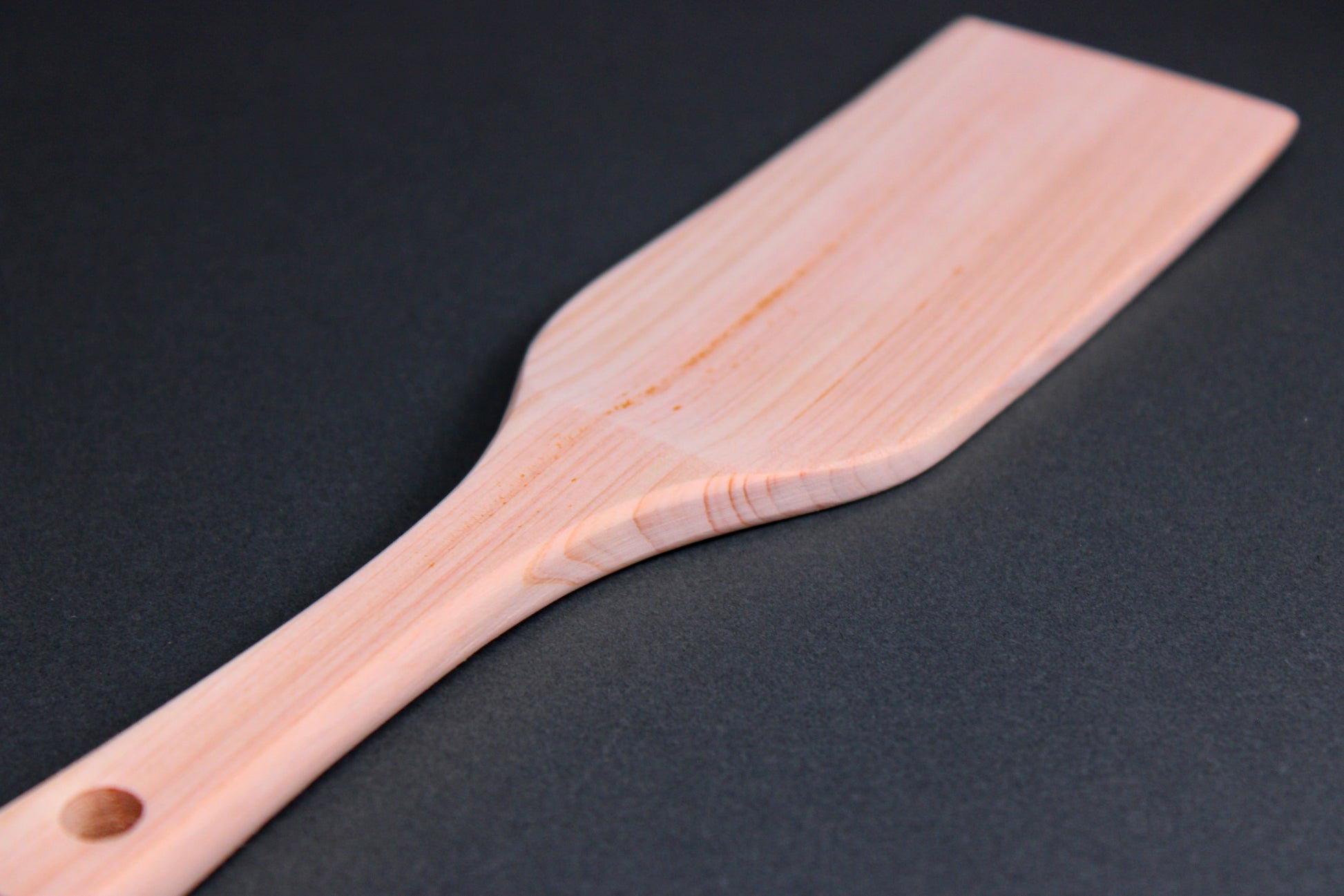 hinoki wood spatula long wide with thin handle and broad spatula area on dark grey surface 