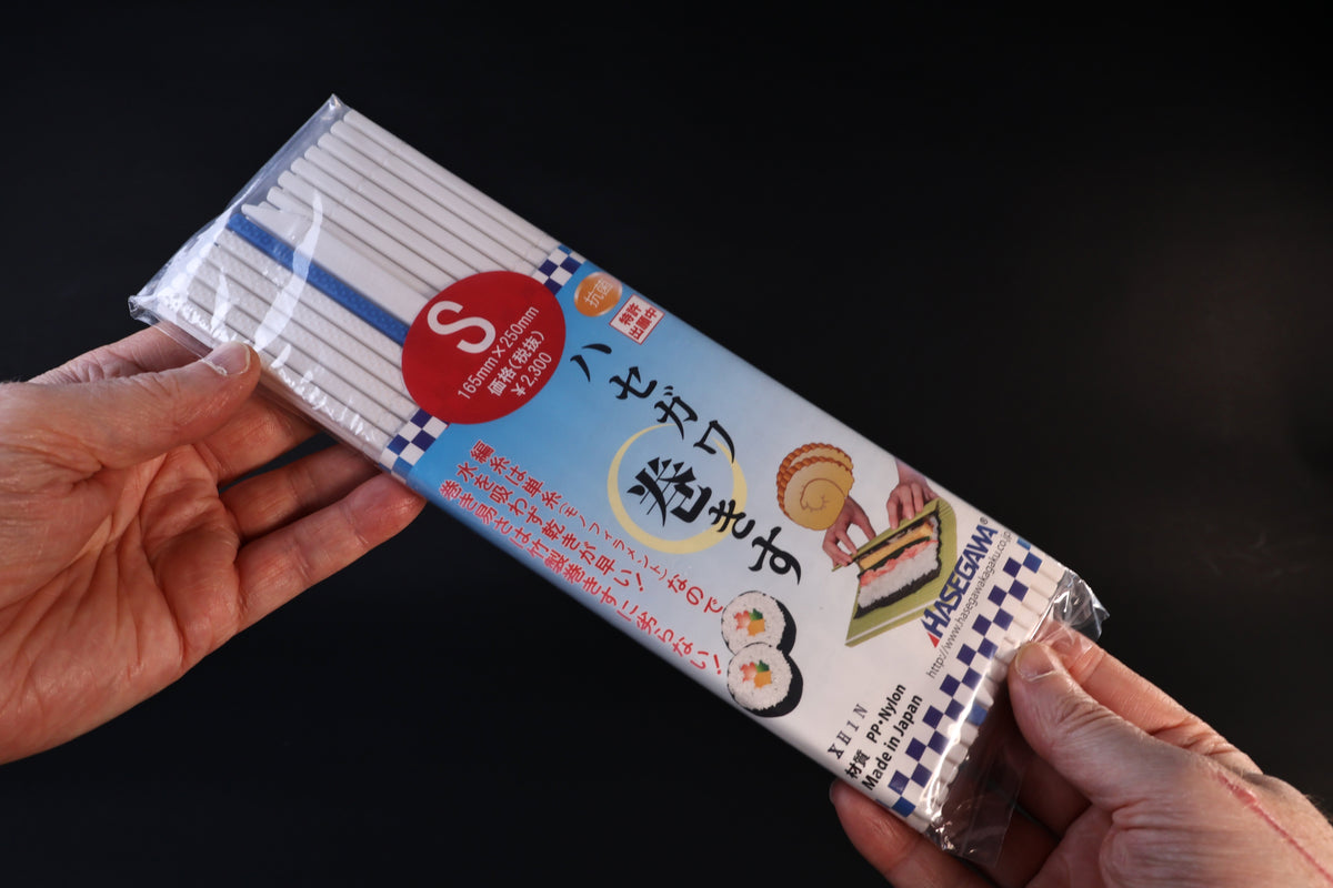 Hasegawa white antibacterial sushi rolling mat in size S packaging, held front side out against a dark background