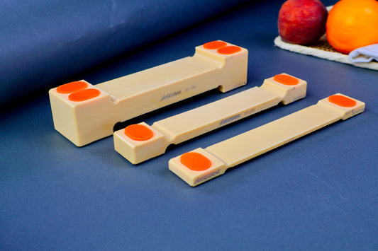 three sizes of hasegawa cutting board lifters long rectangular shaped with pill shaped bright orange oval non slip material in blue grey background with fruit and towel 