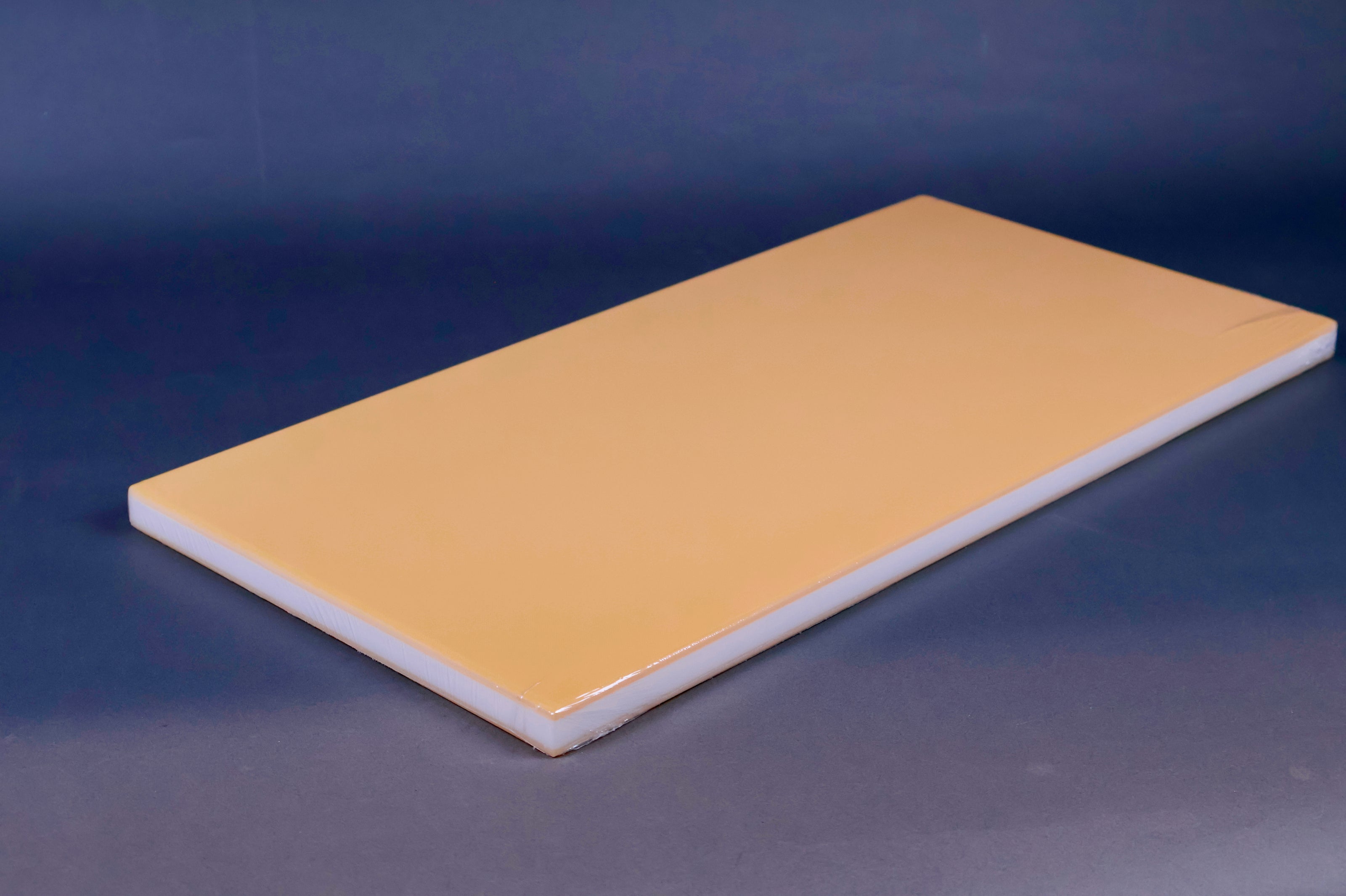 long yellow rectangular shaped rubber cutting board with white sides on grey background