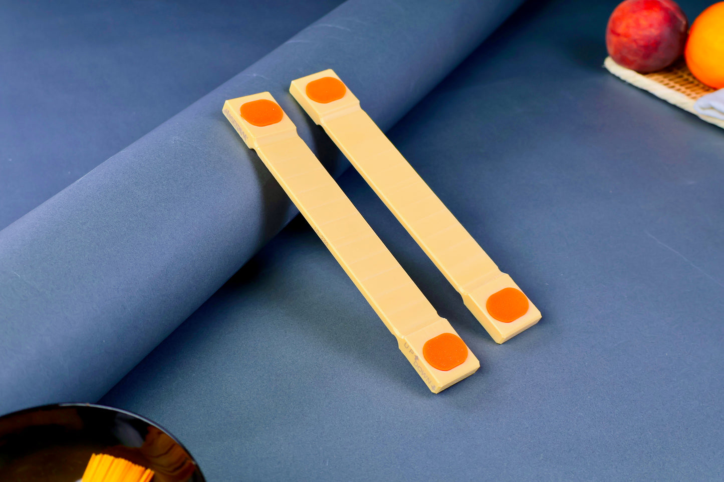 hasegawa cutting board lifters ten mm tall long rectangular shaped with pill shaped bright orange oval non slip material in blue grey background with fruit and towel 