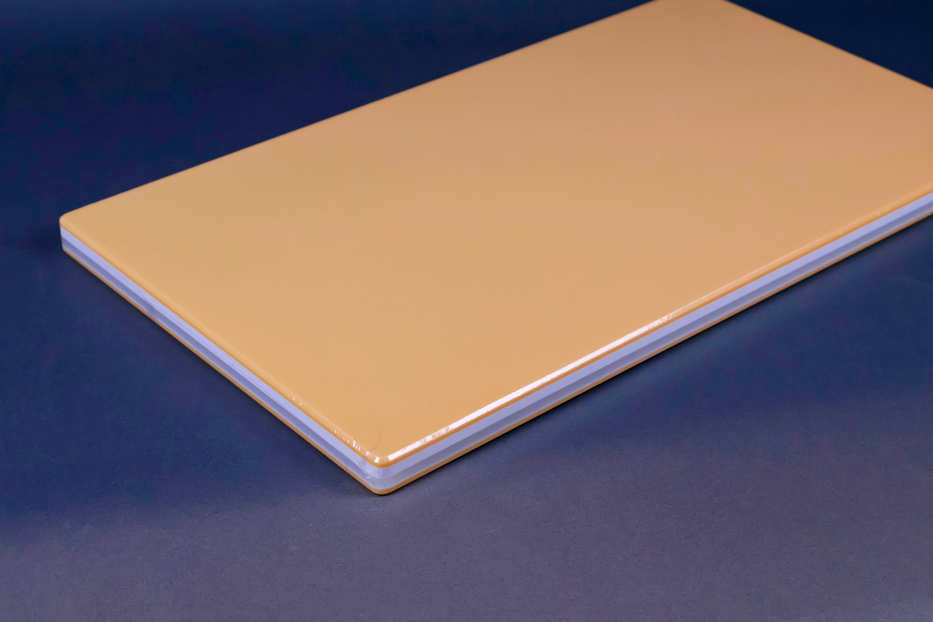 long yellow rectangular shaped rubber cutting board with white and grey stripes surrounded by kitchenware on grey background