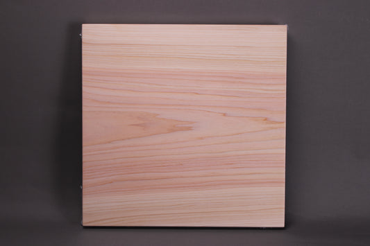 profile of solid piece straight grain hinoki cutting board square shape pinkish hue heartwood and lighter colored outer shade of wood with gre background