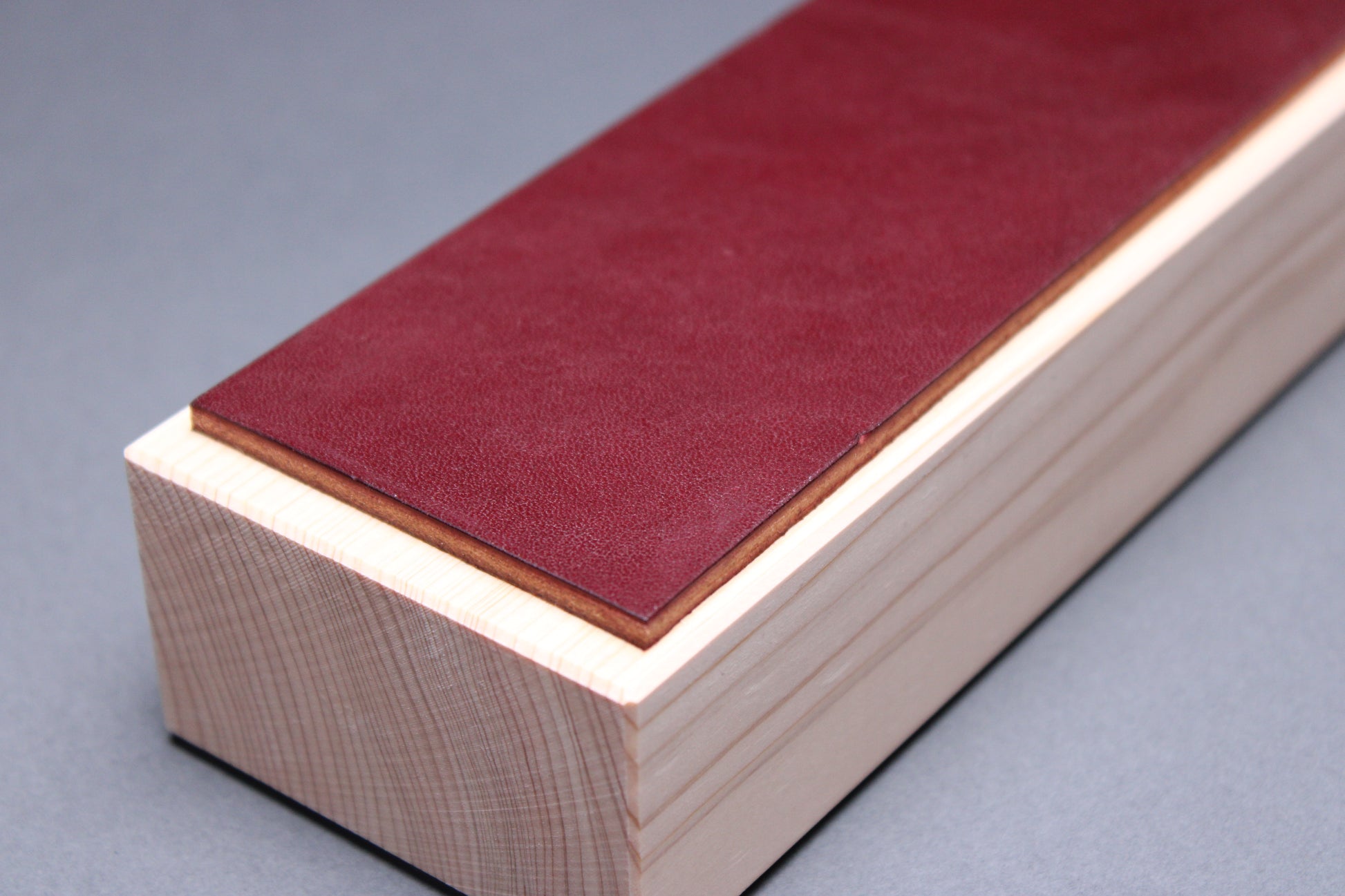 Hinoki espresso leather knife strop — close-up of end showing burgundy leather thickness and hinoki wood grain