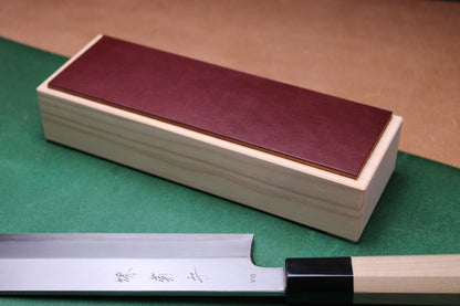 Hinoki espresso leather knife strop — top view with Japanese knife alongside, showing strop in use context
