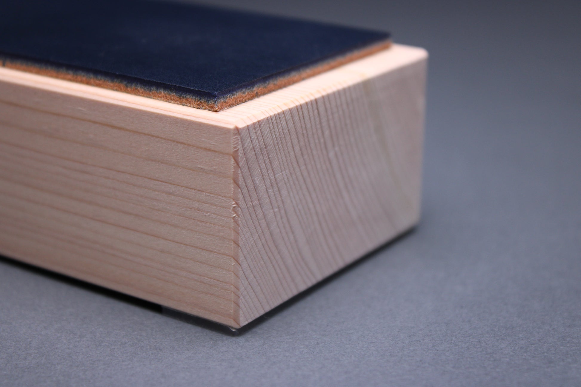 Hinoki midnight leather knife strop — close-up of end showing navy leather thickness and hinoki wood grain