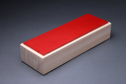 Hinoki vermilion leather knife strop — three-quarter view showing red leather surface on hinoki wood base