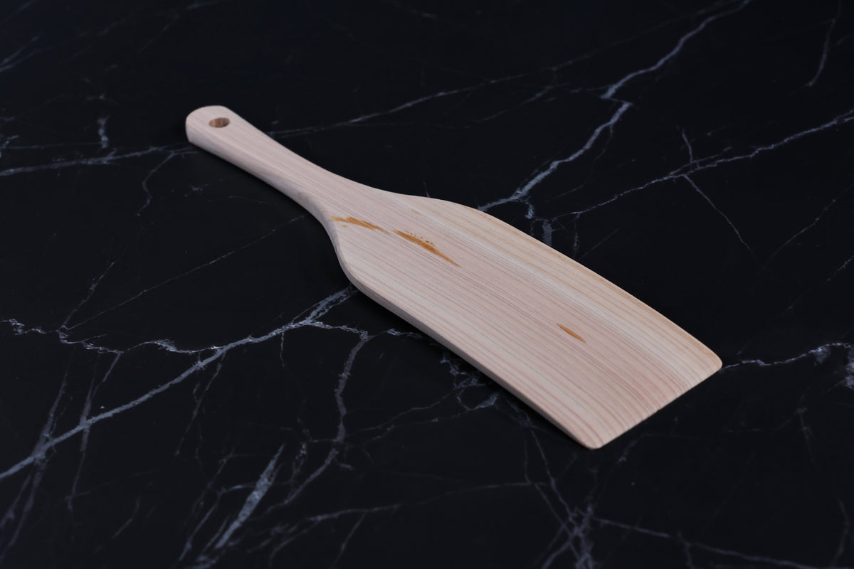 Hinoki wood spatula large — angled view showing blade face, hinoki grain, and handle taper on marble
