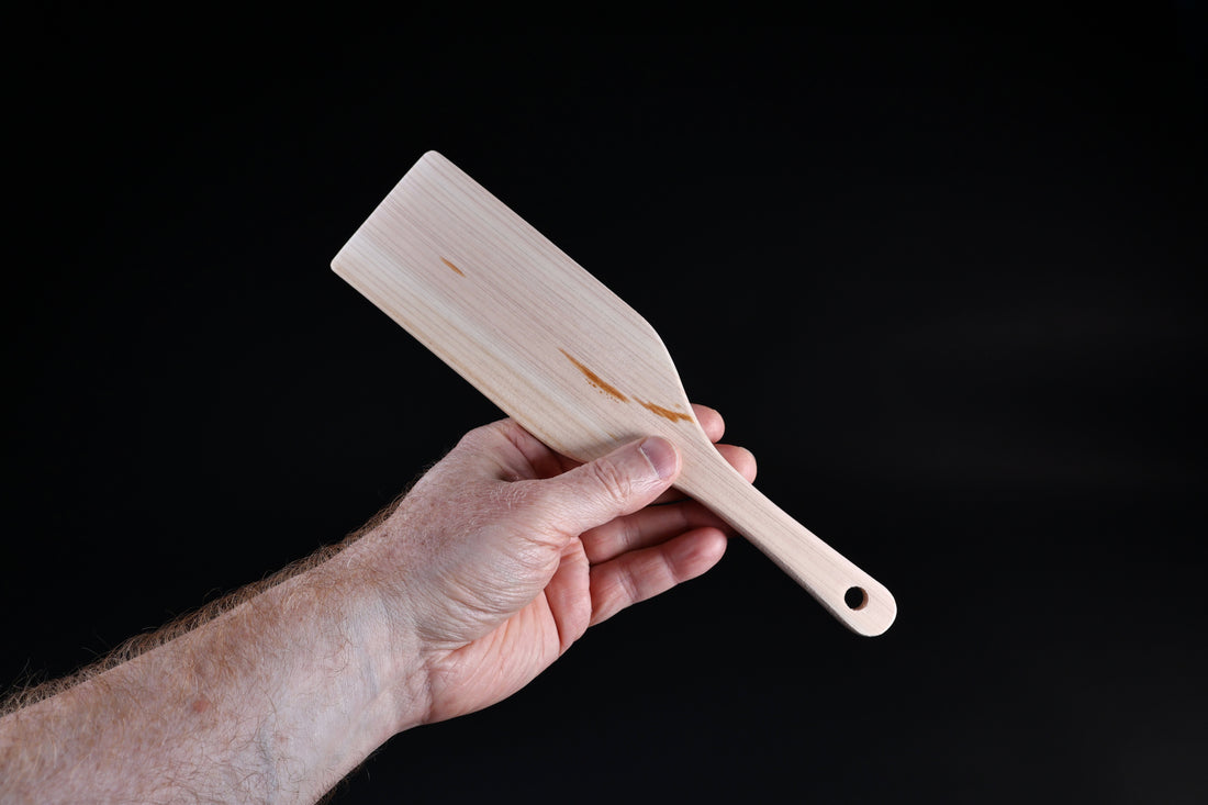 Hinoki wood spatula large — reverse angle showing blade top surface and handle hanging hole in hand
