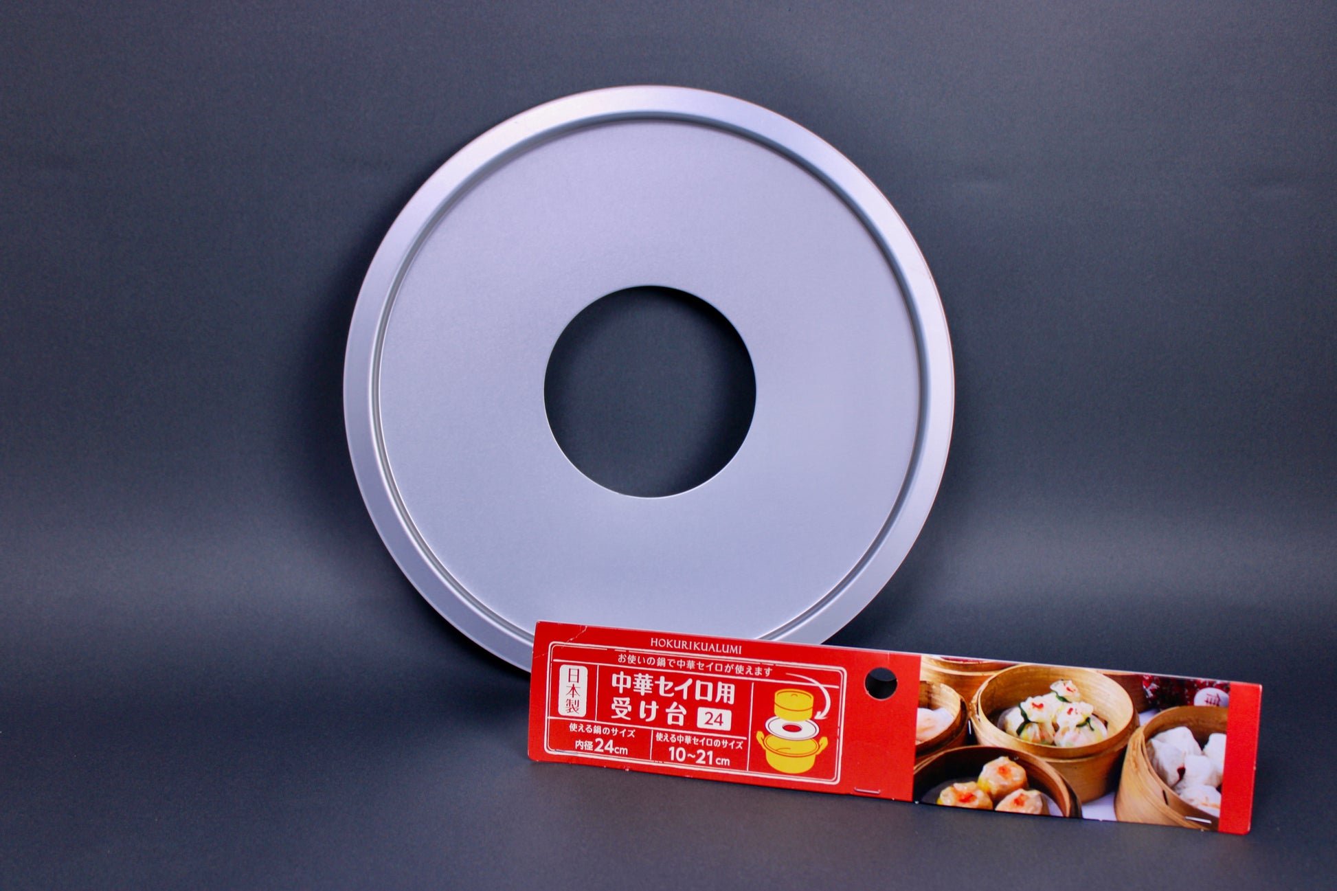 metalic shiny circular steam ring for bamboo steamer center hole next to red yellow white product card showing steamed food dark grey background