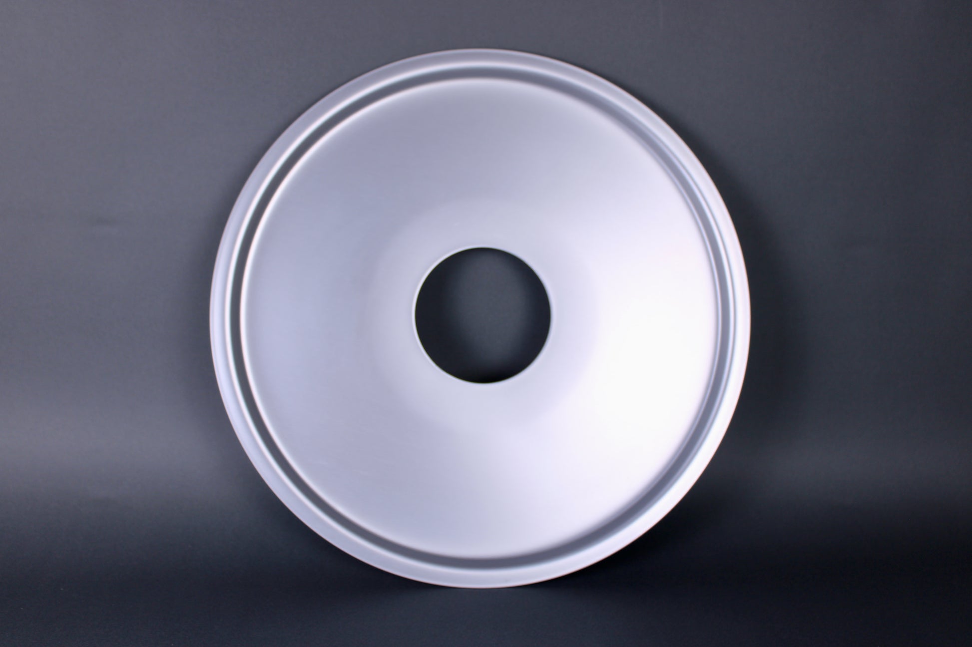 metalic shiny circular steam ring for bamboo steamer center hole dark grey background