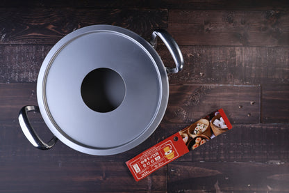 Hokuriku Aluminum steam ring 24cm — seated on double-handle pot, top view with red packaging