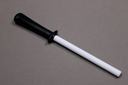 plastic black handled white ceramic honing rod angled on grey background