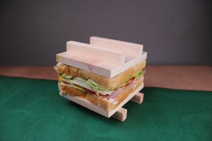 sandwich maker with top and bottom pieces showing sandwich inside on green surface and grey background